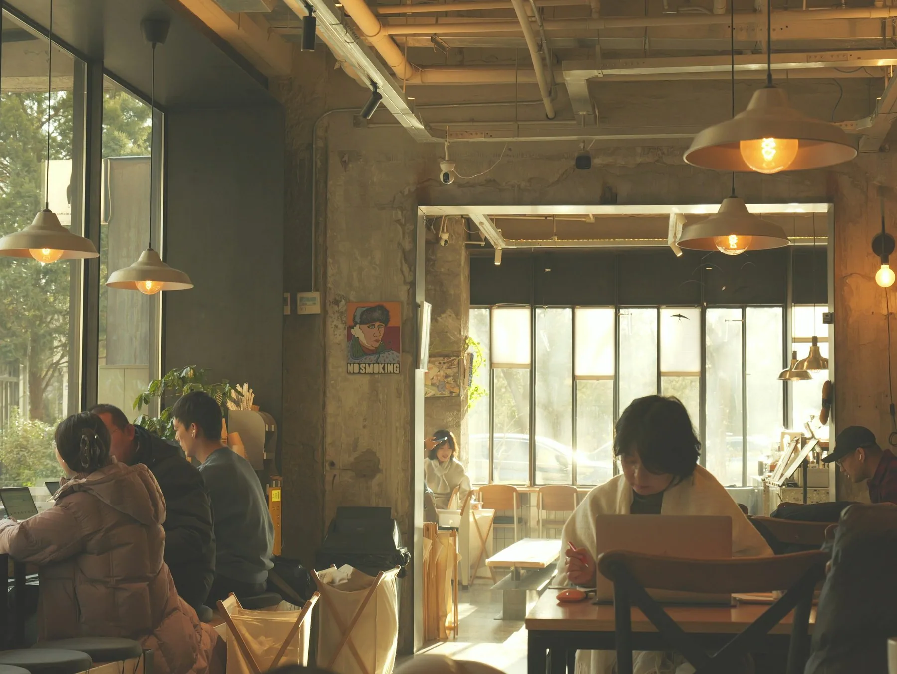 Folk, der arbejder på laptop og slapper af i en solrig café