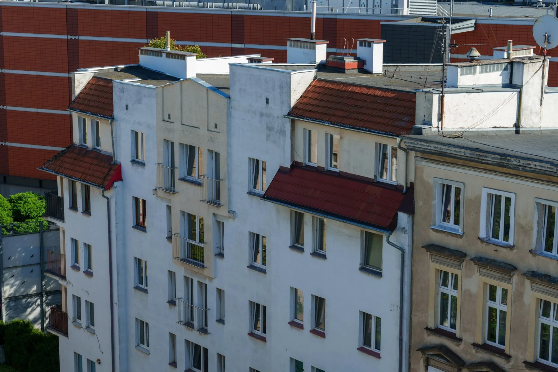 Række af ældre etageejendomme med røde tegltage og mange vinduer i et boligkvarter i Wrocław