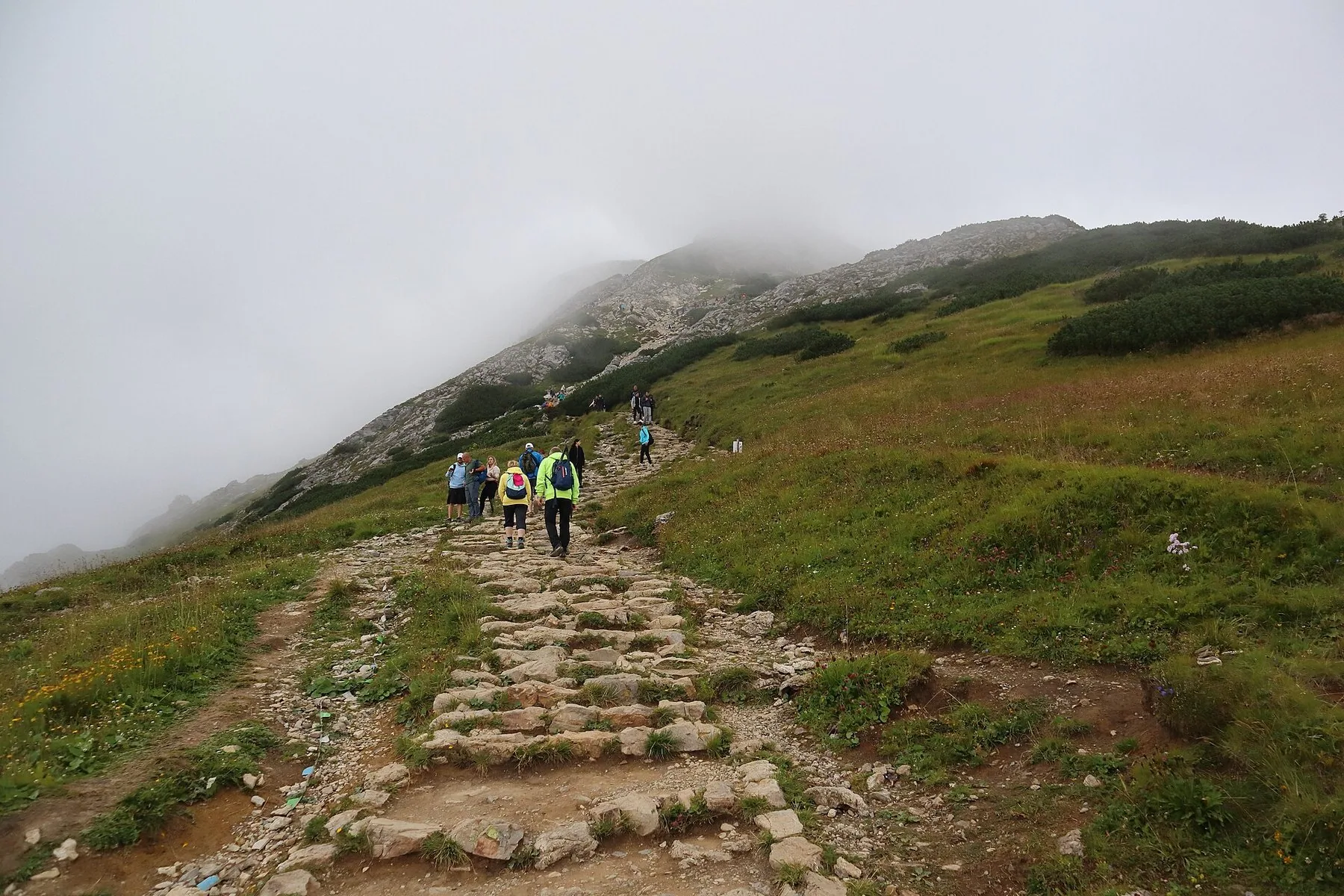 Vandrare på den stensatta leden mot Giewont i Tatra medan låga moln döljer toppen