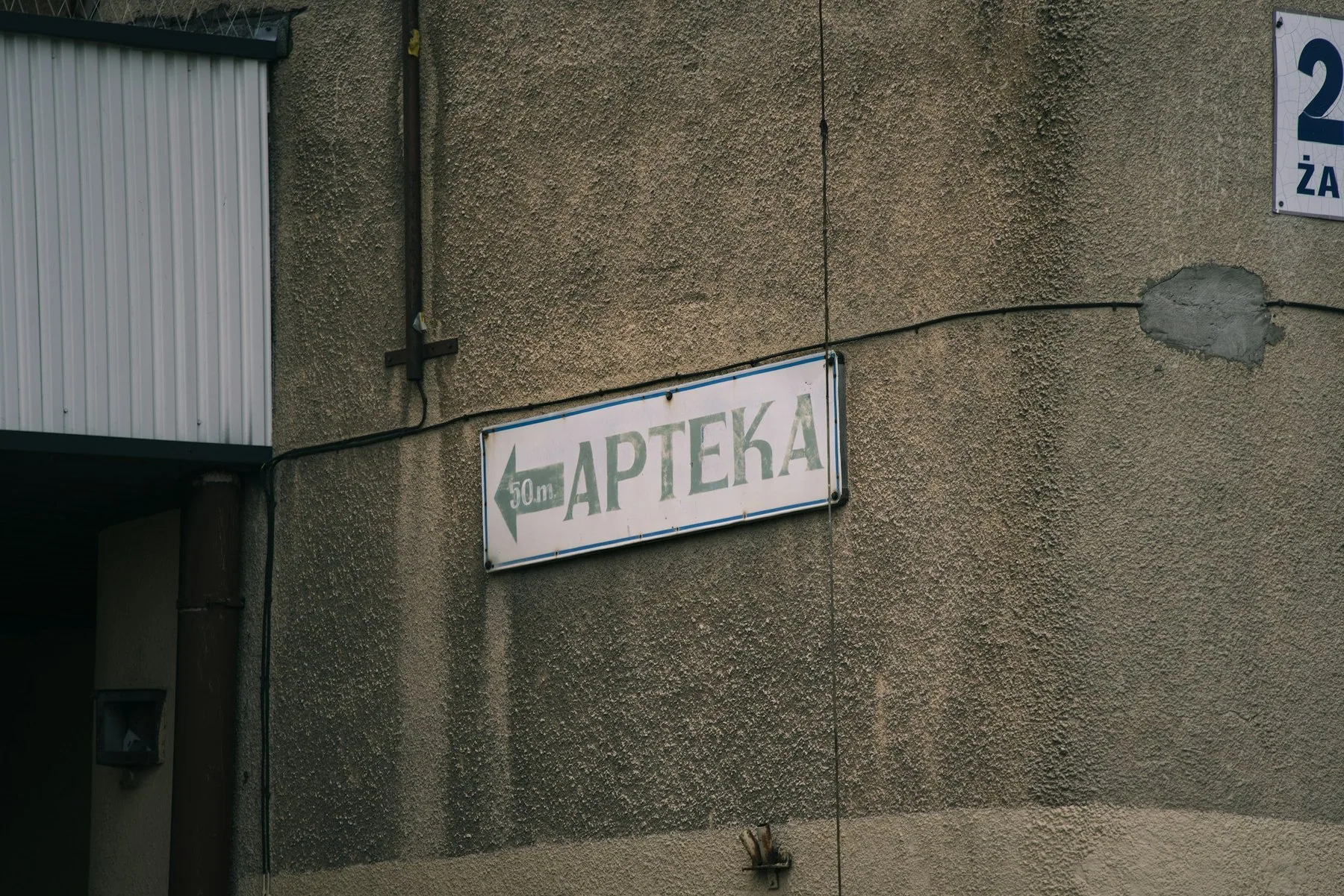 Skylt med pil och texten ”Apteka” (apotek) på en husvägg i Białystok