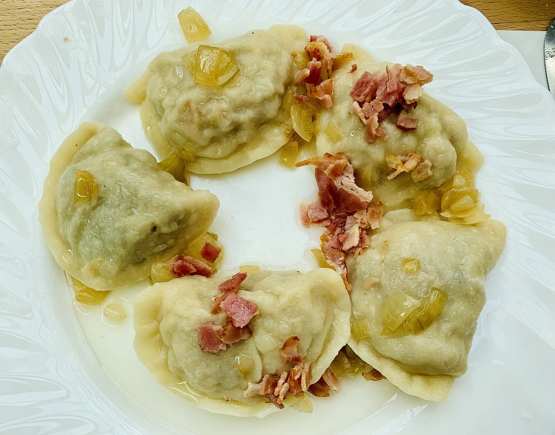 En tallerken kokte pierogi toppet med stekt bacon og løk, servert i Warszawa