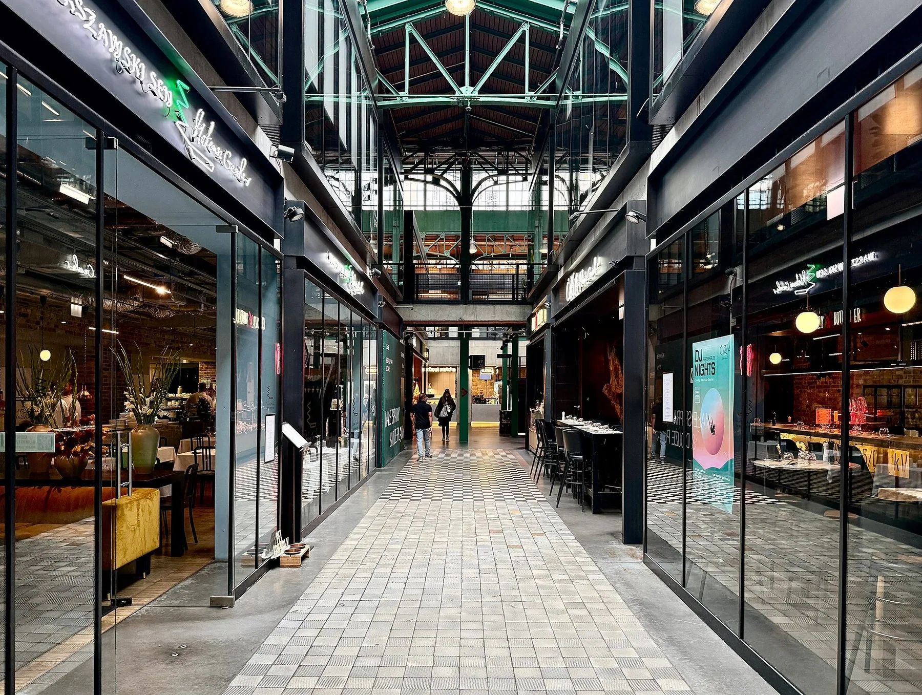Restauranger med glasfasader längs en passage i den restaurerade saluhallen Hala Koszyki i Warszawa
