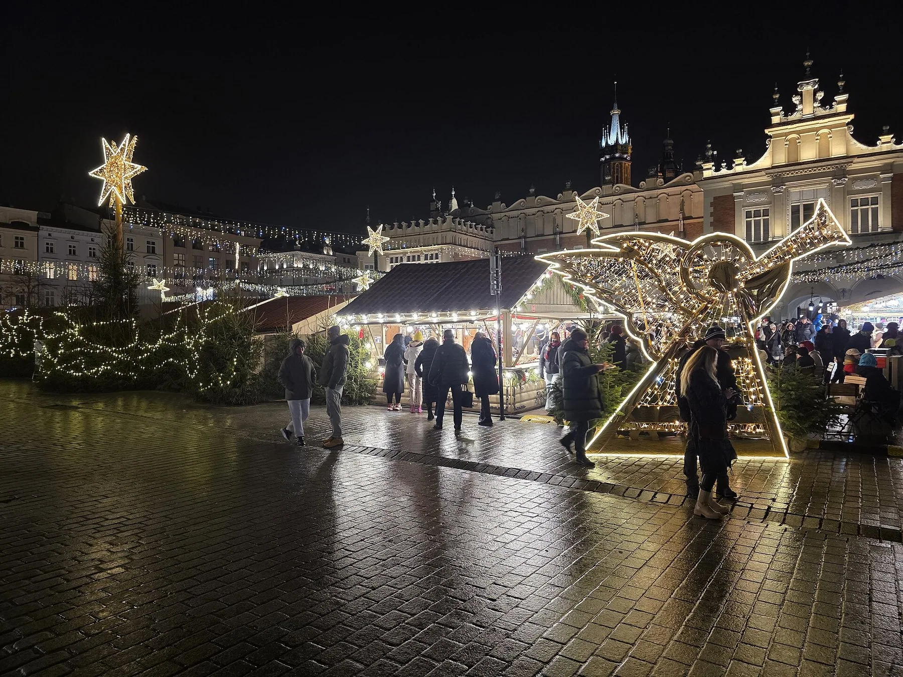 Julemarkedet på Rynek Główny i Kraków om aftenen med lysende stjerner, boder og klædehallen Sukiennice