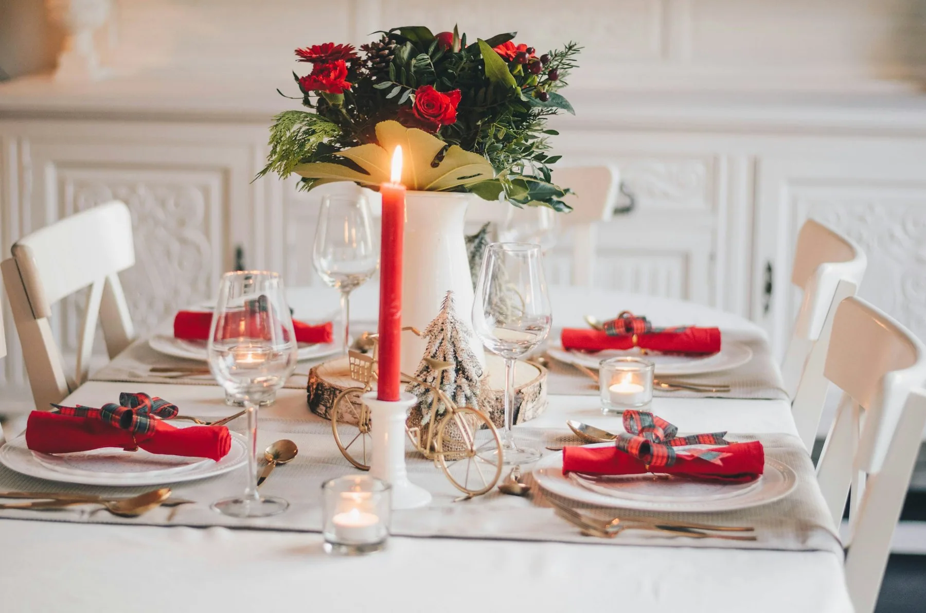 Festdukat bord med blombukett, levande ljus och röda servetter