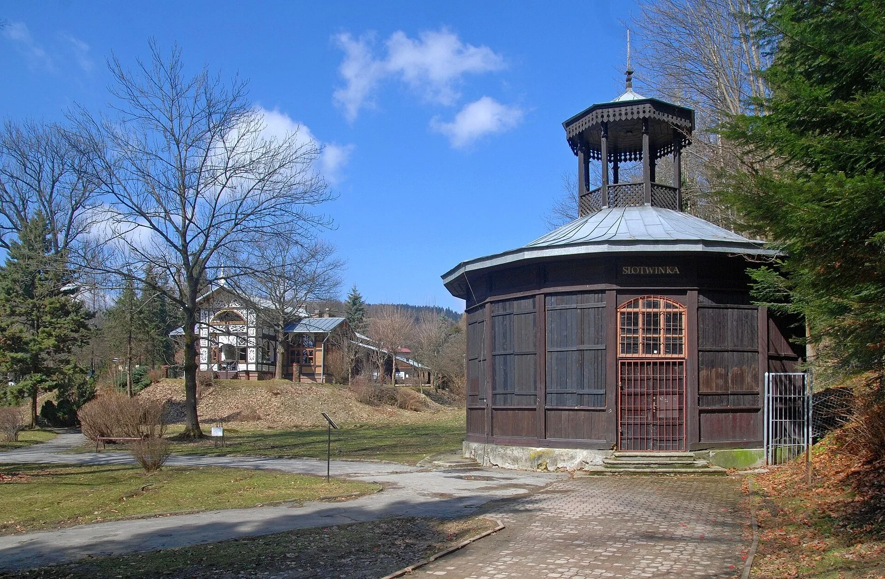 Den åttekantede drikkepaviljongen Słotwinka av tre i kurparken i Krynica-Zdrój, der gjestene drikker mineralvann