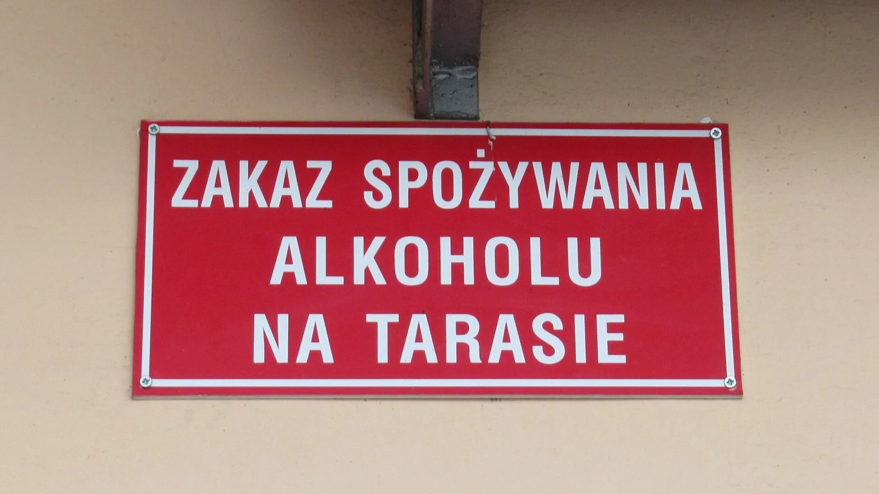 Rødt skilt med teksten «Zakaz spożywania alkoholu na tarasie» – forbud mod alkohol på terrassen