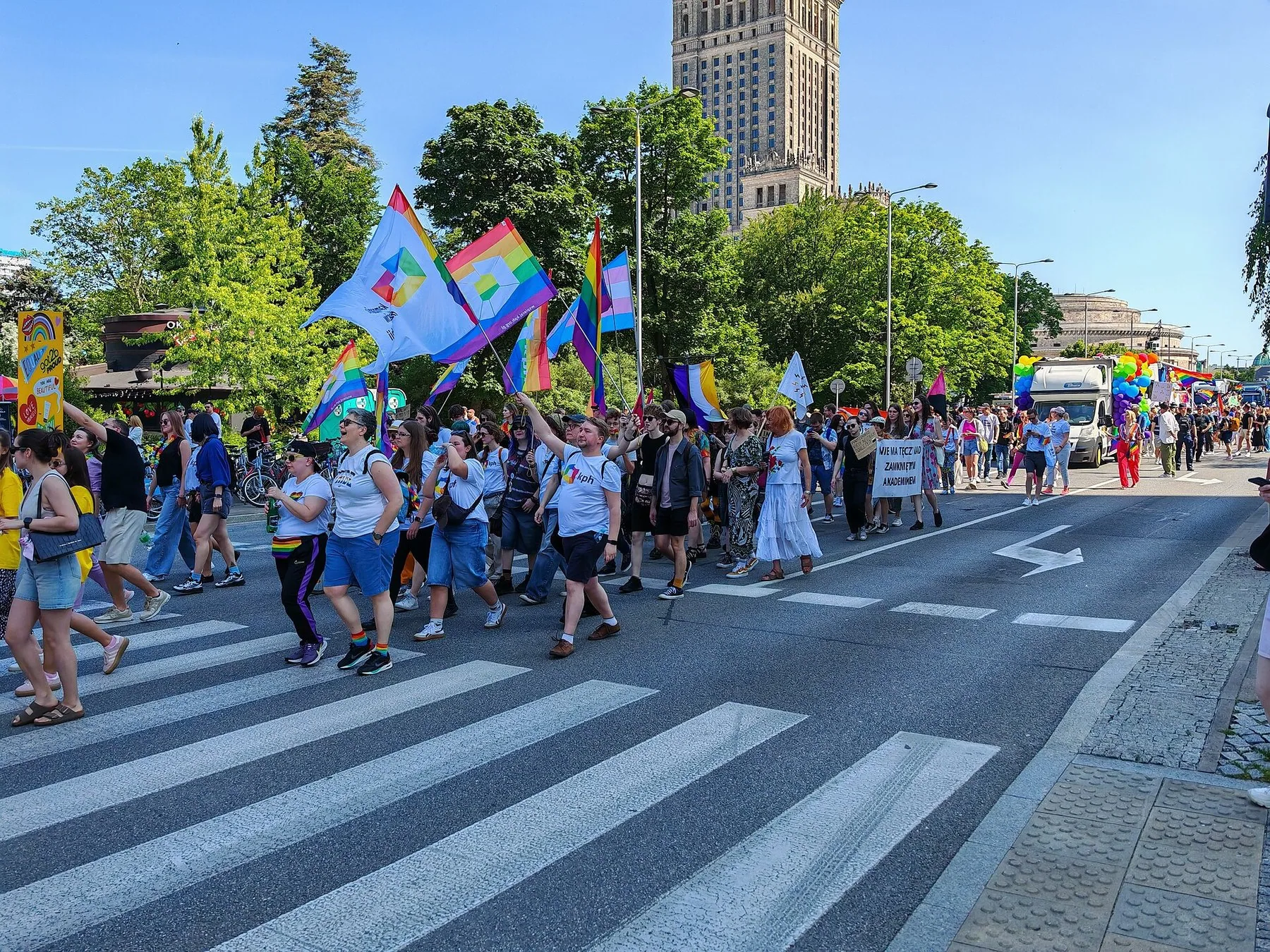 Regnbågsflaggor och deltagare i Parada Równości, jämlikhetsparaden i Warszawa, med Kulturpalatset i bakgrunden