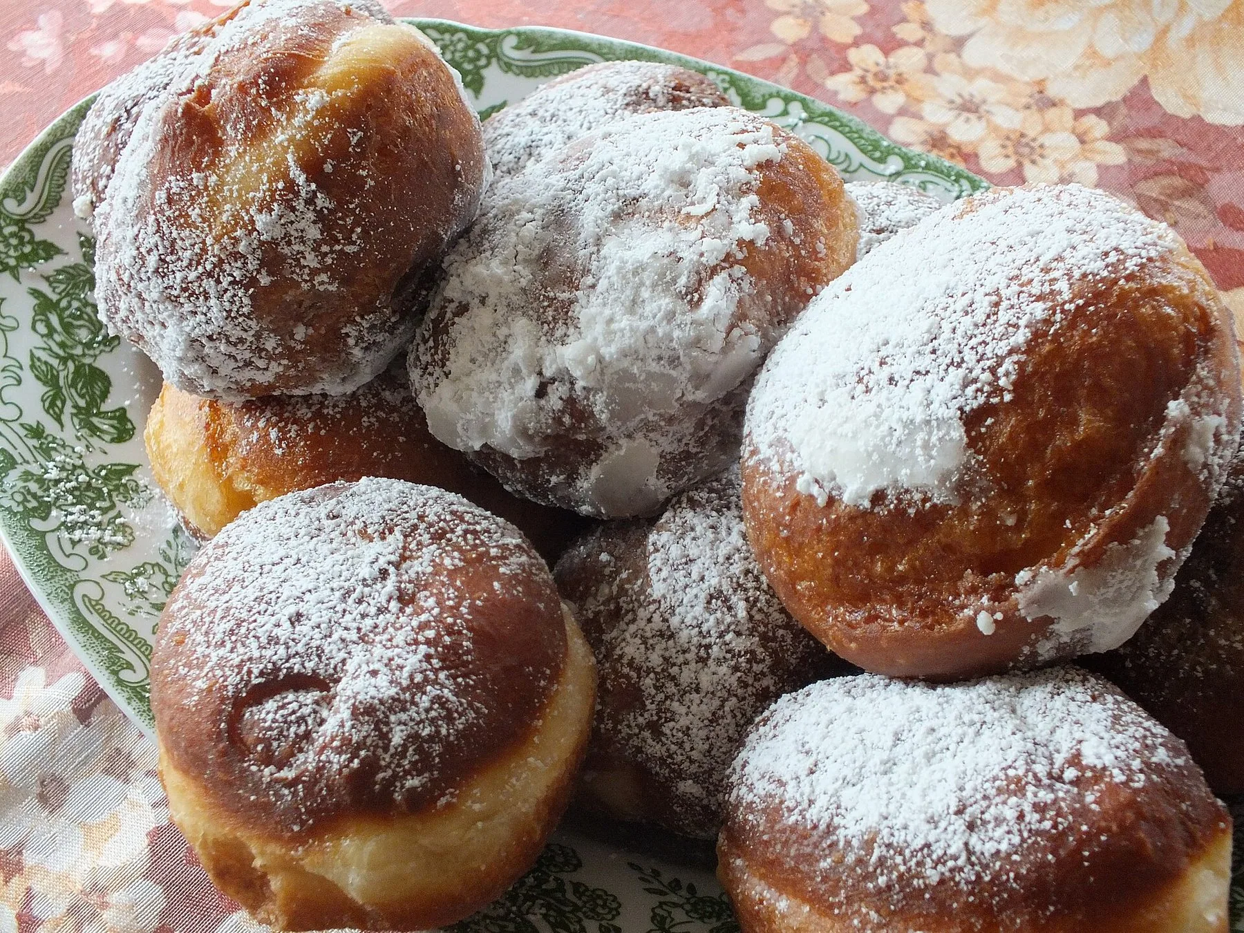 Pączki, polska munkar pudrade med florsocker, på ett blommigt fat