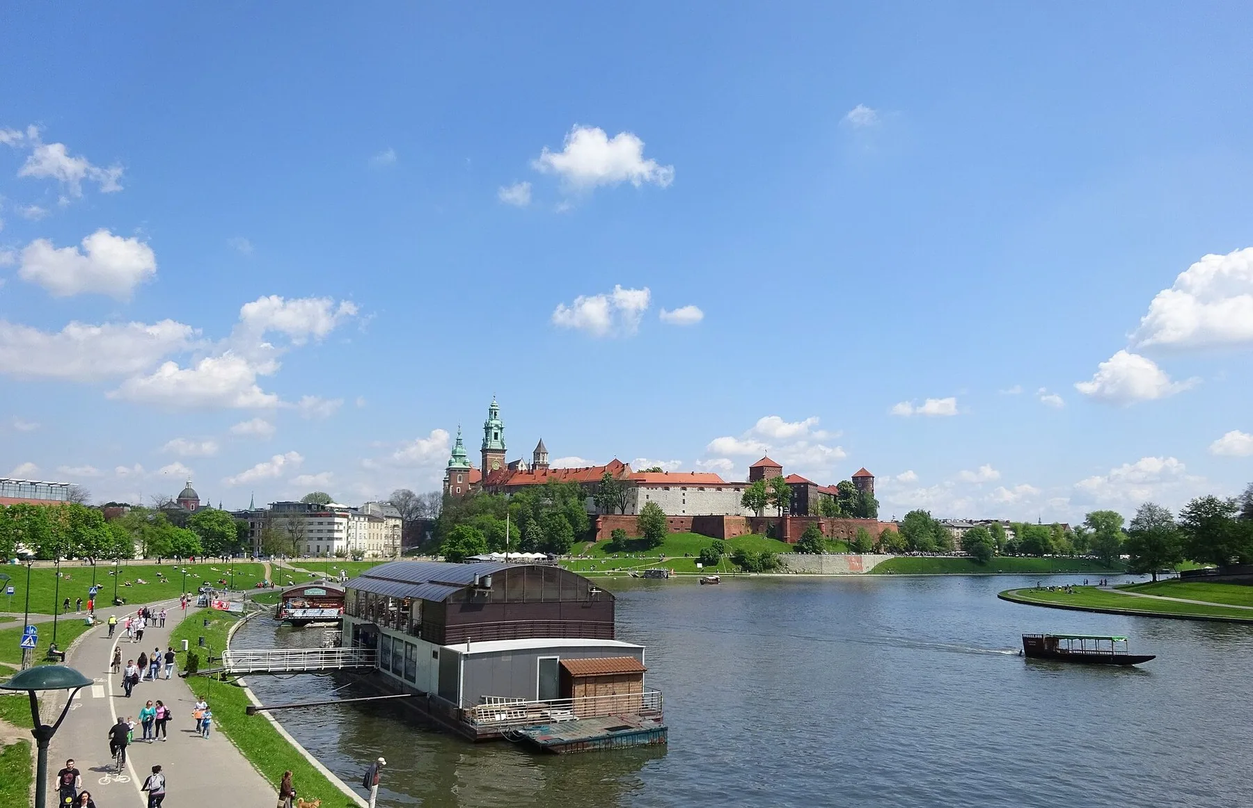 Grønne flodpromenader langs Wisła i Kraków en sommerdag, med Wawel-slottet i baggrunden