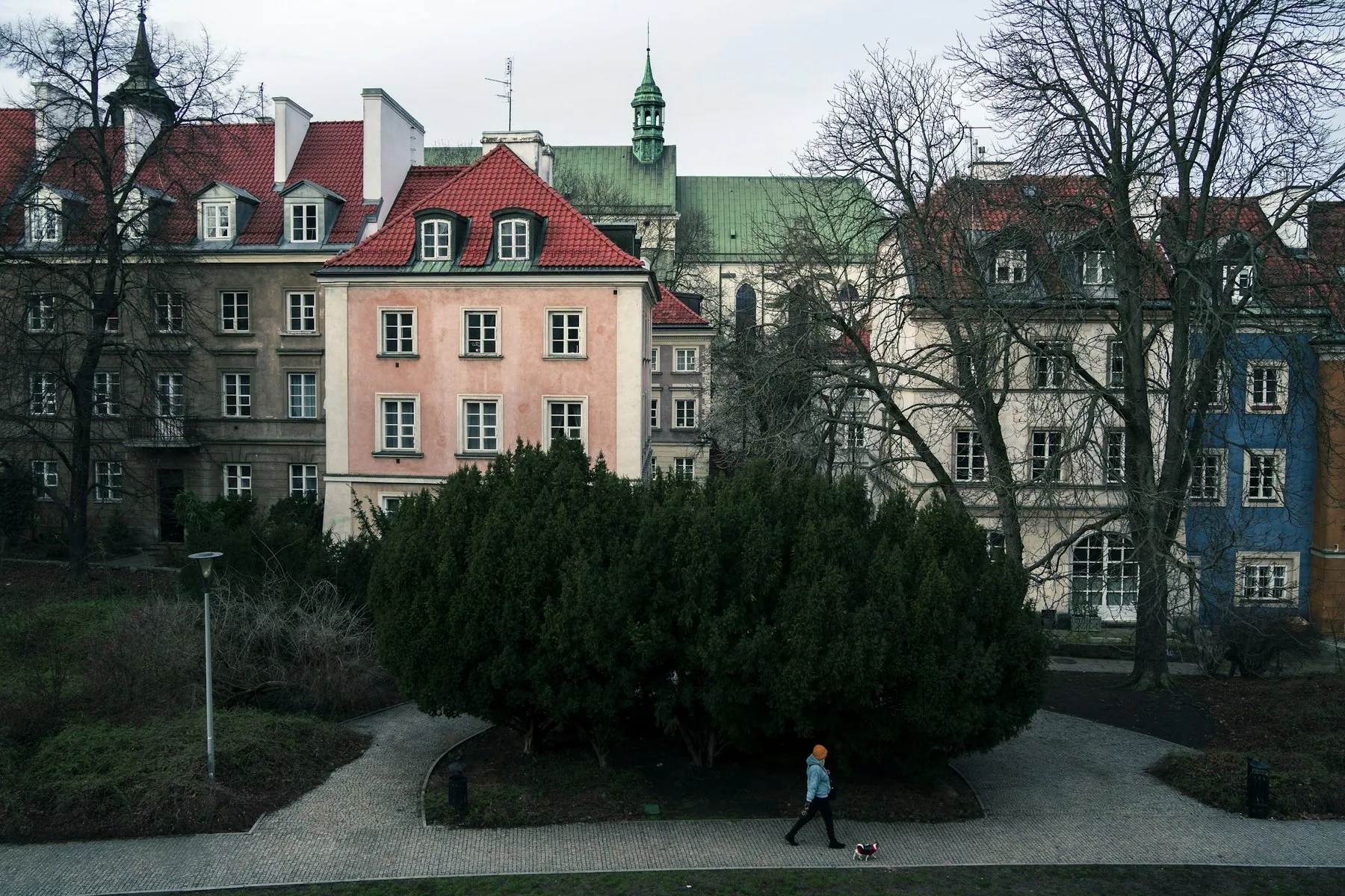 En person går tur med hund i en park ved gamlebyen i Warszawa