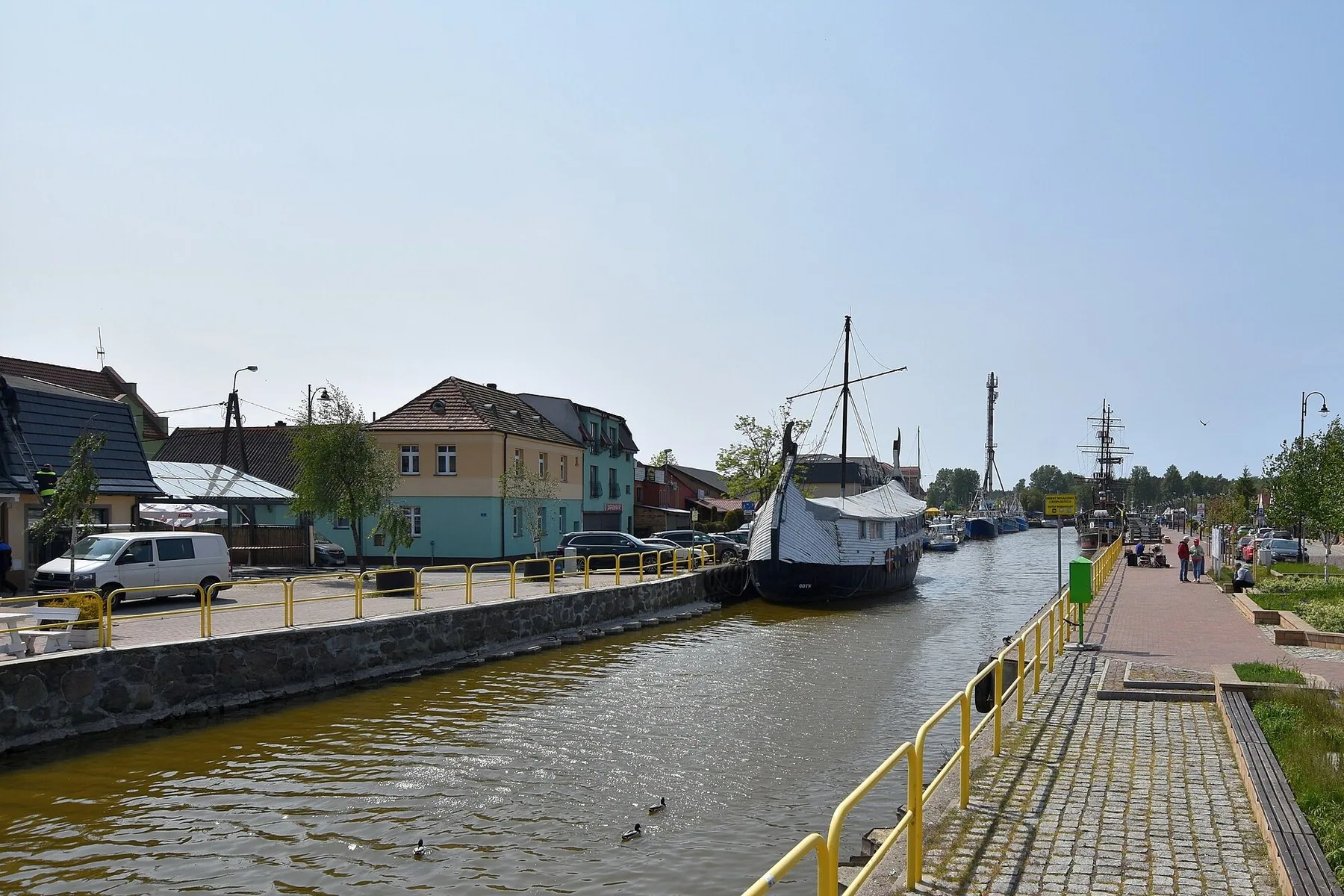 Hamnkanalen i Łeba med en gammal segelskuta vid kajen och hus längs vattnet