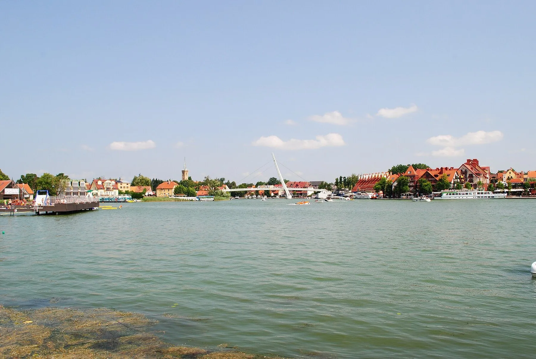 Søen Mikołajskie med småbyen Mikołajki og gæstehavnen på den anden side af vandet en sommerdag