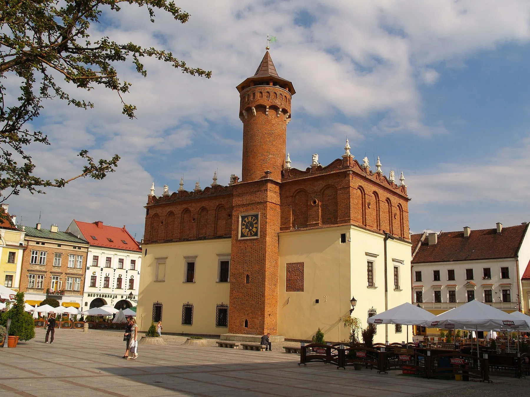 Renässansrådhuset med högt tegeltorn mitt på torget i Tarnów, omgivet av borgarhus