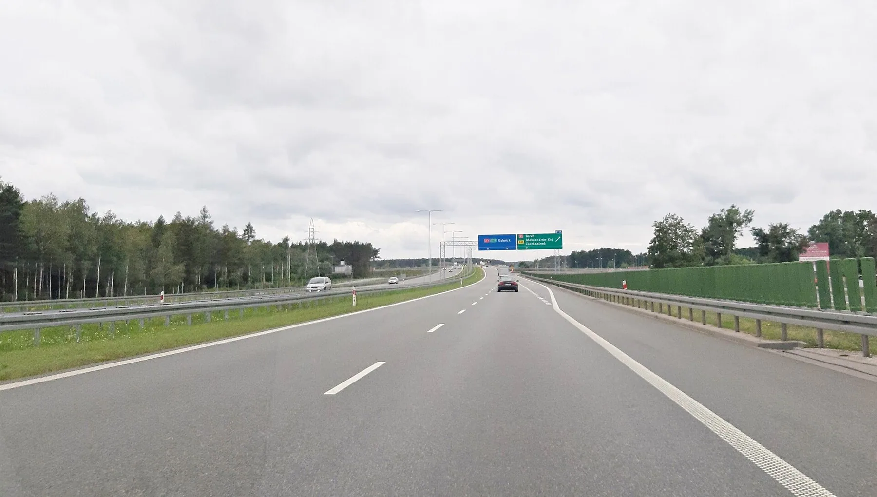 Motorveien A1 ved Włocławek med lite trafikk, autovern og grønne skilt over veien