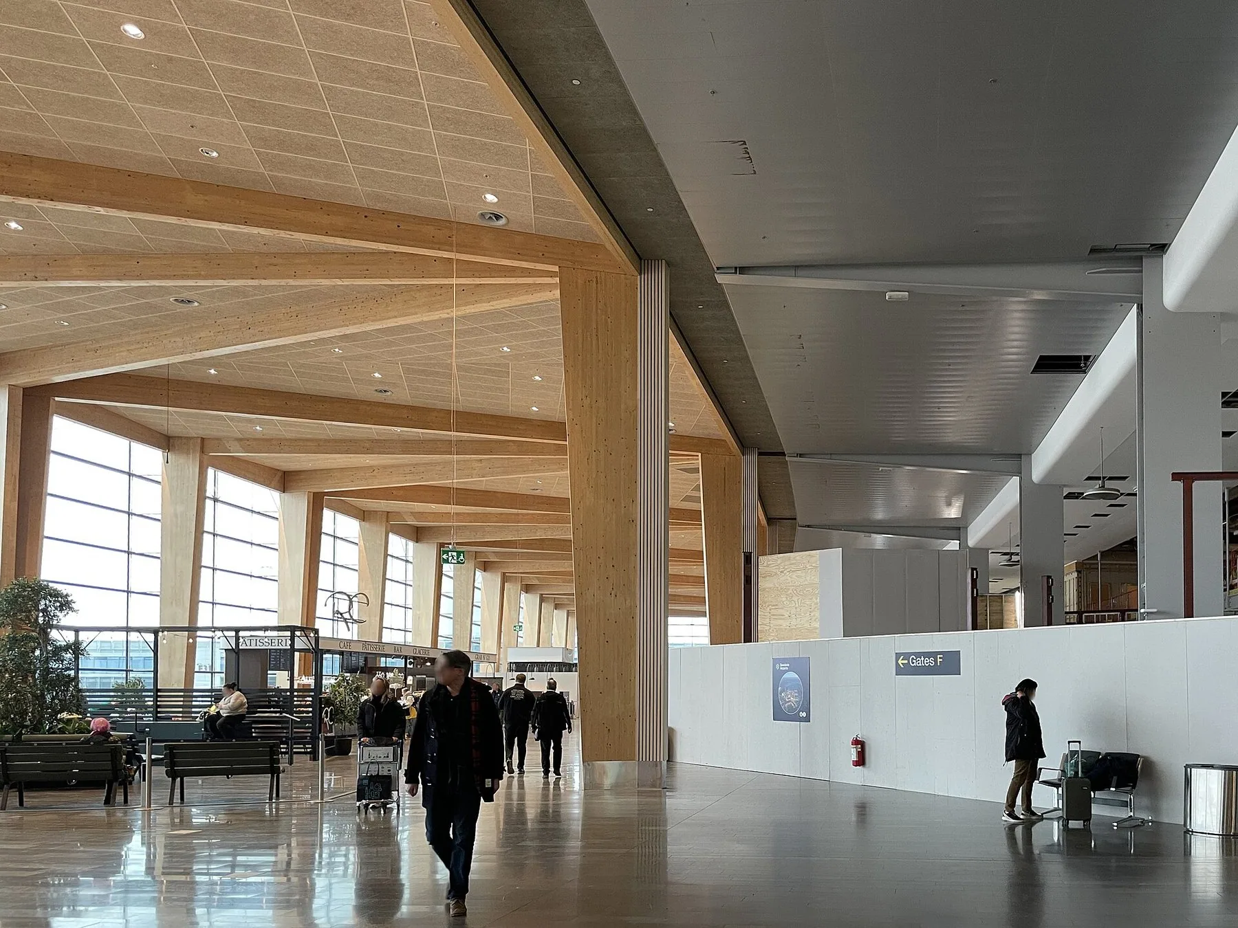 Ljus avgångshall med träbalkar och stora fönster i terminal 5 på Stockholm Arlanda